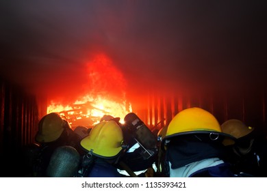 A Group Of Fireman Attacking A Fire With Water. Doing Teamwork ,against Fire Fighting Training In Confined Space . Concept For Emergency ,rescue And Teamwork Concept.