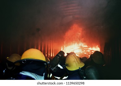 A Group Of Fireman Attacking A Fire With Water. Doing Teamwork ,against Fire Fighting Training In Confined Space . Concept For Emergency ,rescue And Teamwork Concept.