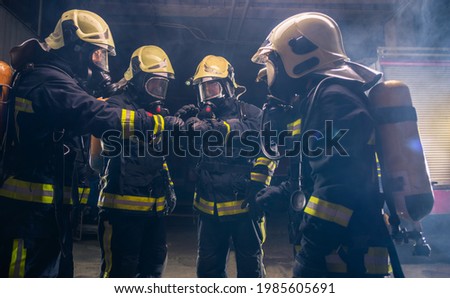 Group of firemen in the fire department organizing action plan for safe execution with gas masks