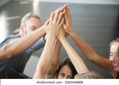 Group of fit happy people giving high five in fitness studio room, talking in a circle after seminar training. Setting goal, achieving team results. Teamwork, mindfulness, active life benefits concept - Powered by Shutterstock