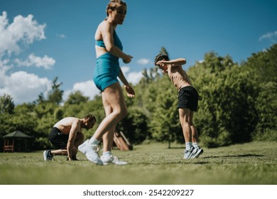 Group of fit individuals performing outdoor exercises in a park. Sunny day with blue skies and green trees in the background. - Powered by Shutterstock