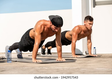 Group of fit young men doing bodyweight push up exercise outdoors on building rooftop - Powered by Shutterstock