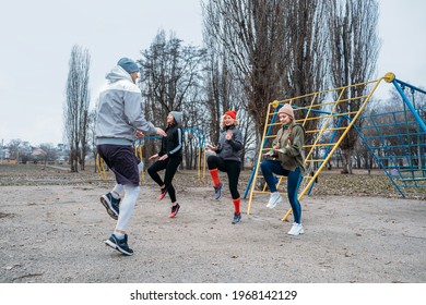 Group Fitness Workout Classes Outdoors. Socially Distant Outdoor Workout Classes In Public Parks. Three Women And Man Training Together In The Public Park. Health, Wellness And Community Concept