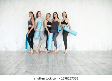 Gruppe der Fitness jungen Frau mit Matten für Yoga steht an der Wand.  Gesunder Lebensstil