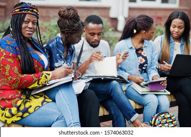 Group of five african college students spending time together on campus at university yard.  friends studying at bench with school items, laptops notebooks. - Shutterstock ID 1574063032