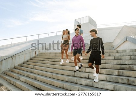 A group of five athletes are talking while walking down the stairs