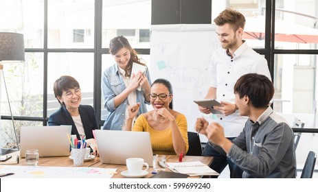 Group Of Five Creative Worker Brainstorm In Office, Two Senior Review And Comment On Junior Officer's Work