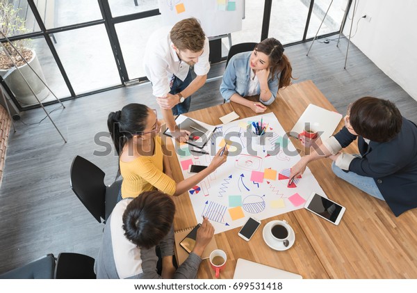 Grupp av fem kreativa arbetare brainstorm tillsammans på kontoret, ny stil av arbetsyta, glad scen av människor i kontor