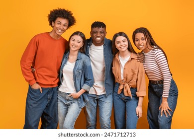 Group of five diverse young adults standing in front of a yellow background. They are all smiling and looking at the camera. The group appears to be friends and is enjoying each others company. - Powered by Shutterstock