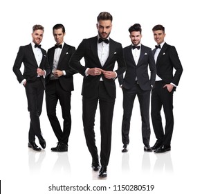 group of five elegant men wearing black tuxedoes with leader buttoning suit and stepping in front of them, full body picture - Powered by Shutterstock