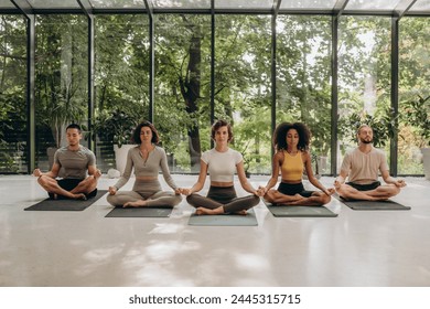 Group of five friends gathering in studio to practice yoga - Powered by Shutterstock