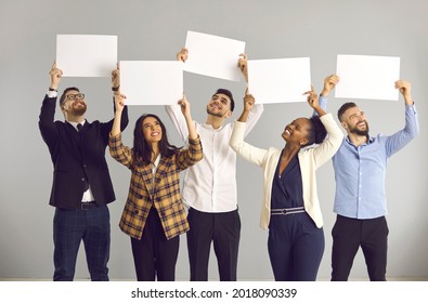 Group Of Five Happy Smiling People, Office Workers Or Friends, Standing On Gray Background, Holding White Sheets Of Paper, Empty Signs, Mockup Banners, Expressing Opinion Or Giving Positive Feedback