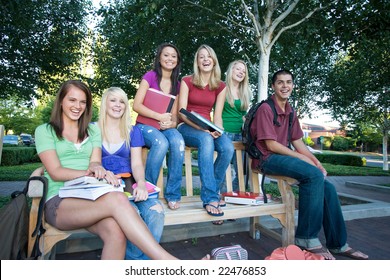 Group Of Five Laughing High School Girls And One Boy Sitting On A Bench Holding Books. Horizontally Framed Photo.