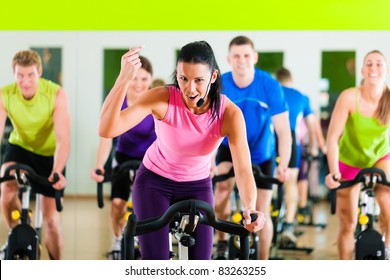 Group of five people - men and women - in gym or fitness club exercising their legs doing cardio training; the trainer is in front - Powered by Shutterstock