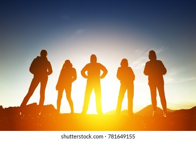 Group of five peoples silhouettes in sunset light