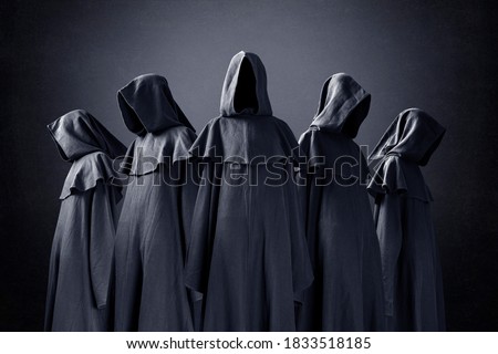 Group of five scary figures in hooded cloaks in the dark
