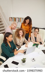 Group of five stylish sucessful women working together on new business project using laptop vertical shot
