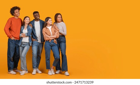 A group of five young adults multiracial friends stand together in front of a vibrant yellow backdrop, looking at copy space - Powered by Shutterstock