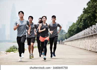 Group Of Five Young Asian Adult Men And Woman Running Training Outdoors