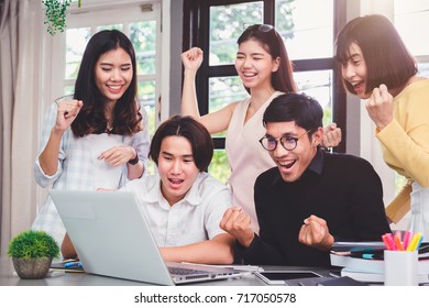 Group Of Five Young Euphoric Students Watching Exam Results In A Laptop In A Table Of An University Campus Bar.