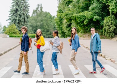 Group of Five Youth People Crossing Road On Crosswalk. University students crosses the road at a pedestrian crossing. Hipster teen millennials on a walk on a day off.