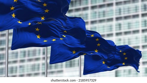 group of flags of the European Union waving in the wind in front of the European Parliament building. - Shutterstock ID 2185957329