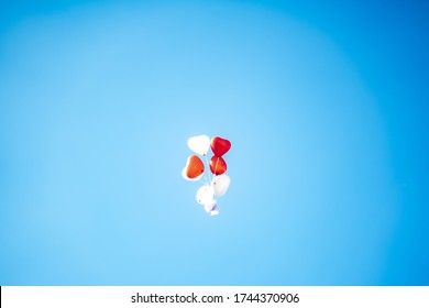 Group Of Flying Heart Shape Balloons. Bunch Of Red And White Helium Filled Balloons Against Blue Sky. Copy Space.