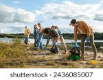 A group of focused volunteers diligently clears litter from a picturesque lakeshore under a cloudy sky. Active Volunteers Participating in a Lakeshore Cleanup Campaign. High quality photo
