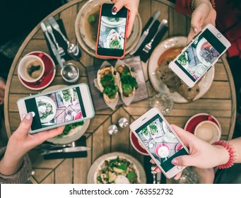 Group Of Food Bloggers Taking Photo Of Dishes In The Restaurant Table. Top View. Friends Lunch, Social Media Funs