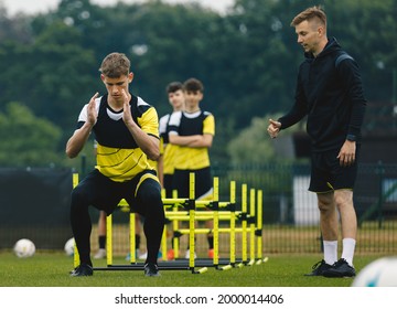 Group of Football Players on Agility Training. Young Coach Giving Advices to Player on Training. Coaching Soccer in Teenage Football Team - Powered by Shutterstock