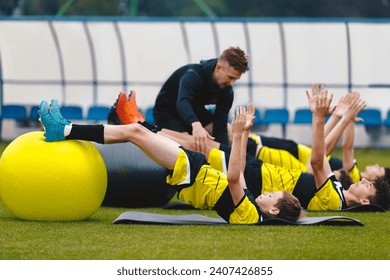 Group of Football Players on Physiotherapy Training. Young Trainer Giving Advice to Player on Agility Training and Stretching. Coaching Soccer in Team - Powered by Shutterstock