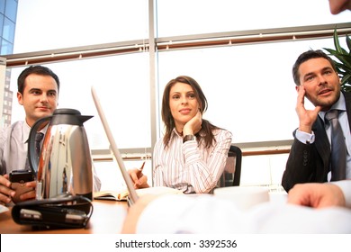 A group of four business people gather around a conference room table for a working discussion to plan a new project.