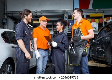Group of four car service technician men and woman talking at workplace, people working together at vehicle repair garage service shop, check and repair customer car at automobile service center. 