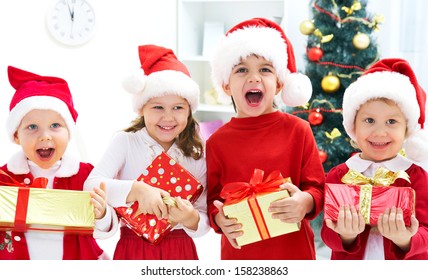 Group Of Four Children In Christmas Hat With Presents