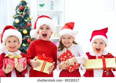 Group Of Four Children In Christmas Hat With Presents