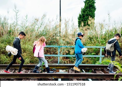 Group of four children hiking in the woods walking in a train track