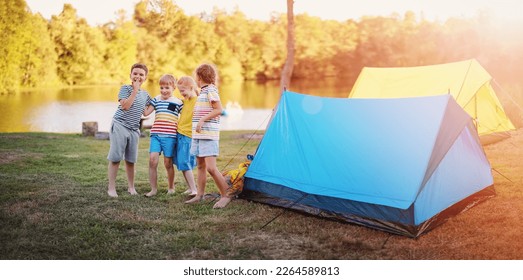 Group of four children standing near colourful tents in nature. Concept of the family vacation, recreation and scouts camping. - Powered by Shutterstock