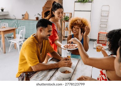 Group of four close friends sharing laughter and snacks during a joyous celebration indoors