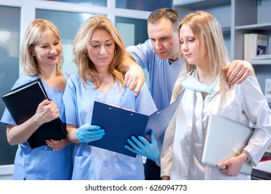 Group Of Four Dentist Working Together In Dental Office.