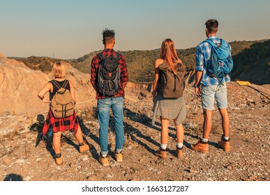 Group of four friends hiking through countryside together at sunset. - Powered by Shutterstock