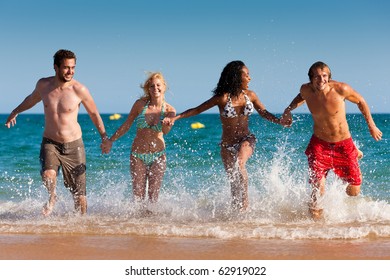 Group of Four friends - men and women - on the beach having lots of fun in their vacation - Powered by Shutterstock