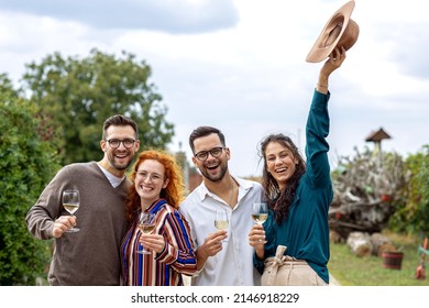Group of four friends in vineyard standing with glass of vine talk and smile
