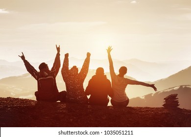 Group of four happy friends is having fun with raised hands against sunset mountains - Powered by Shutterstock