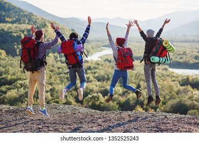 Group of four happy friends jumps at the sunset on mountains background. Traveling, tourism and friendship concept. View from back. - Powered by Shutterstock