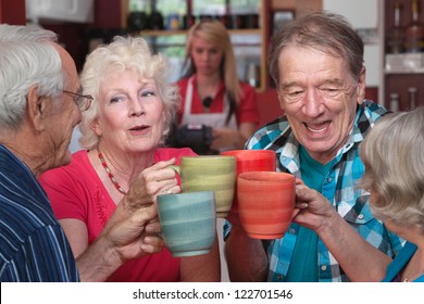 Group of four happy seniors with mugs toasting - Powered by Shutterstock