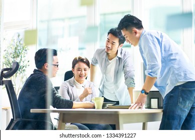 Group Of Four Happy Young Asian Corporate Executives Working Together Meeting In Office Discussing Business In Office.