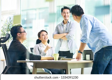 group of four happy young asian corporate people teammates meeting discussing business in office.