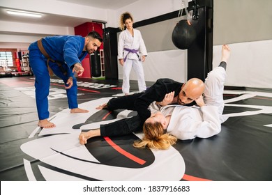 Group Of Four Judo Martial Arts Partners And An Instructor Practicing New Techniques On A Gym Mat