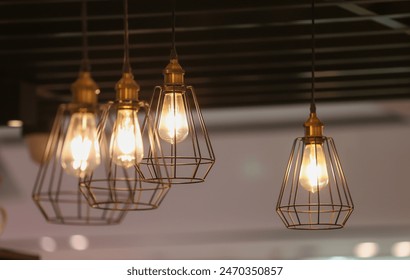 A group of four lighted lamps hanging from the ceiling. The lamps are all different sizes and shapes, but they all have a similar design. The lamps are lit up, creating a warm and inviting atmosphere - Powered by Shutterstock