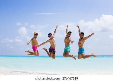 Group Of Four Men Jumping At The Beach